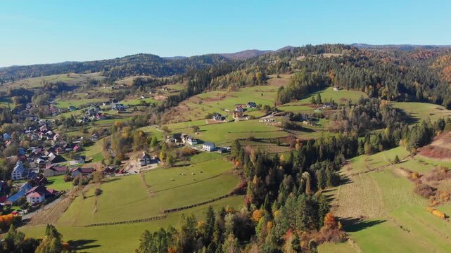 Aerial drone footage of the village of Szlembark on Podhale in Małopolska, with rolling hills, scattered houses and fields, and a distant panoramic view of the Tatra Mountains near Nowy Targ in southe