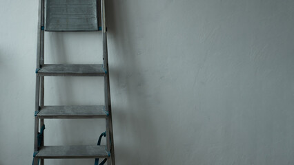 Renovation, house repair. Ladder on the background of gray wall. Copy space.