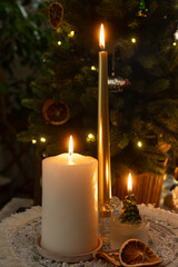 Christmas candles glowing against background of Christmas tree. Winter holidays, cozy home concept.