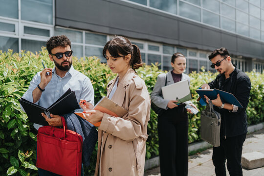 Four businesspeople convening outside, collaborating on projects, and sharing ideas near an office complex.