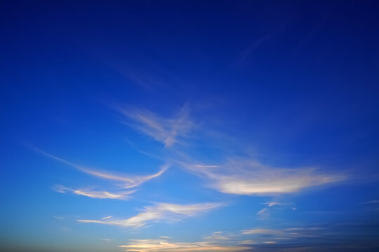 Vast deep blue sky with wispy clouds illuminated by golden sunset light
