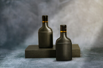 Two elegant black cosmetic bottles standing against a textured gray background. This minimalist mockup is perfect for branding, product packaging previews, advertising materials, and modern design