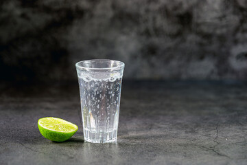 Vodka. Shots, glasses with vodka soda with ice and lime on gray background