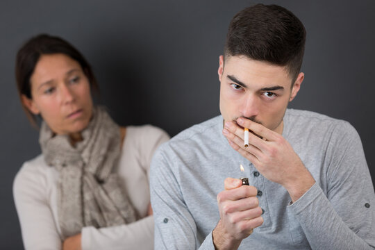 young man smoking cigarette and get caught by his mother