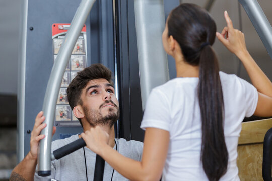 gym instructor helping a client - Powered by Adobe