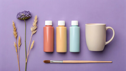 Three paint bottles ceramic mug and paintbrush on purple