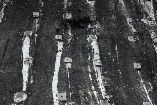 an abstract photograph of soil nailing, a geotechnical engineering technique used for slope stabilization. This method reinforces existing ground by installing closely spaced steel bars (nails)