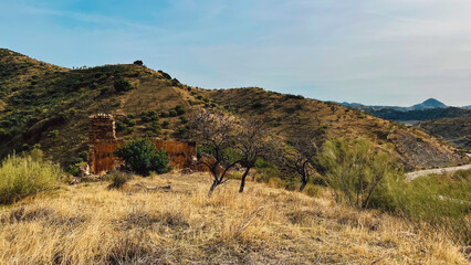 Ruined spanish house in hills with dried vegetation under blue sky. Malaga, Andalusia, Spain. © ysbrandcosijn