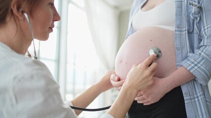 Doctor examining pregnant woman holding stethoscope near big belly listening baby heartbeat. Gynecologist doctor consulting patient about pregnancy in hospital office. Visit to doctor medical checkup - Powered by Adobe