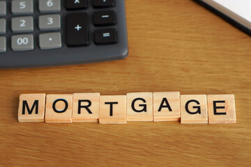 mortgage concept. word written in wooden letters with a calculator and a notebook in the background