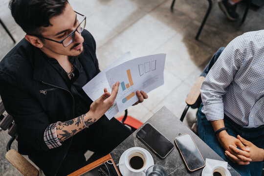 Two colleagues discussing business data and analyzing charts in an informal setting. - Powered by Adobe