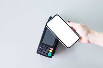Contactless payment. Hand holding smartphone  with blank white screen on payment terminal. Money transfer and mobile banking concept
