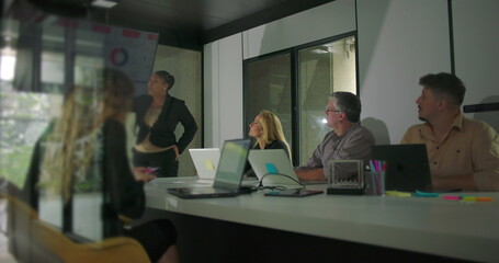 African American businesswoman presenting in office meeting while diverse team listens attentively...