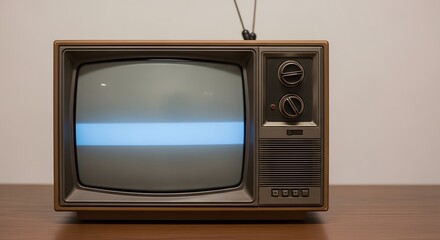 A vintage television set with antenna on a wooden surface against a plain backdrop