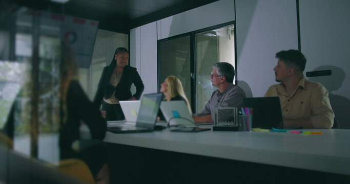African American businesswoman presenting key data to attentive colleagues during corporate meeting in modern office conference room