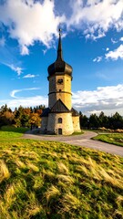 Scenic church steeple on a grassy hill under a partly cloudy sky