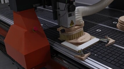 CNC machine mills a wooden workpiece, the operator controls the process using a hand-held remote control. Modern high-precision woodworking production and automation.