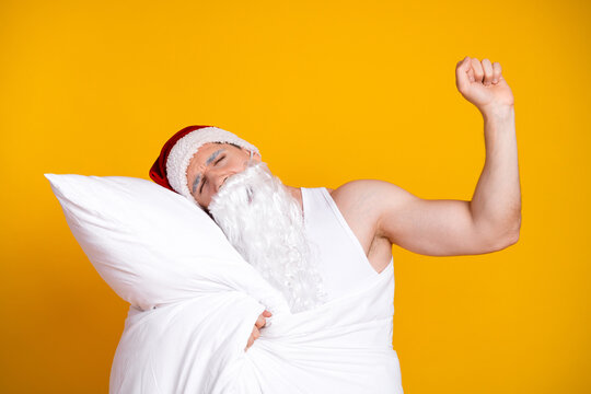 Santa in pajama rests on a pillow with a bright yellow background creating a cozy festive home mood for Christmas and holiday campaigns