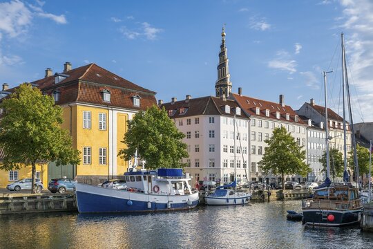 Sailing boats, historic buildings and tower of Vor Frelsers Kirke or Church of the Saviour, Christianshavn Canal, Copenhagen, Denmark