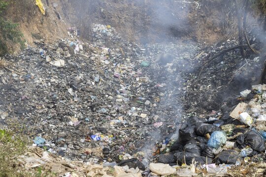 Coking rubbish dump, rubbish pit with waste and plastic rubbish, karst landscape near Vang Vieng, Vientiane province, Laos