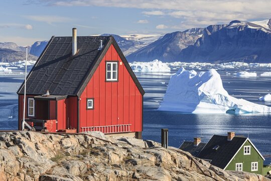 Typical Greenlandic houses in front of icebergs, Inuit settlement, summer, sunny, Uummannaq, West Greenland, Greenland