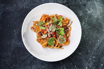 Spicy noodles with chicken, peppers, fresh herbs, and sesame seeds