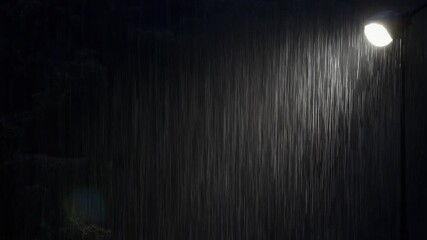 A streetlight illuminated in the rain at night.