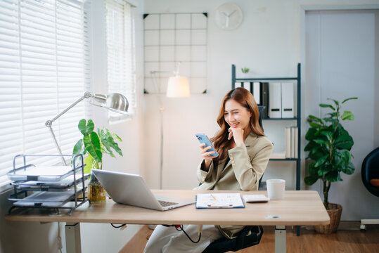 Confident business expert attractive smiling young woman typing laptop and holding digital tablet in green office