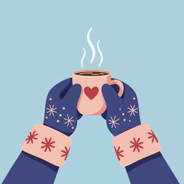 Warm hands holding a cup of hot beverage in winter with heart design on mug 