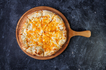 Cheesy Baked Pizza On Wooden Paddle Served On Dark Textured Tabletop