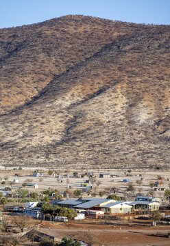 Dry red and white hills in the evening light, houses in the village of Epupa, Kaokoveld, Kunene, Namibia