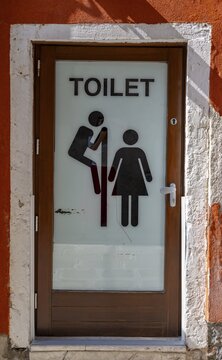 Entrance door to a public toilet, funny, pictogram with man looking over a partition wall at a woman, voyeurism, inscription Toilet, Venice, Veneto, Italy