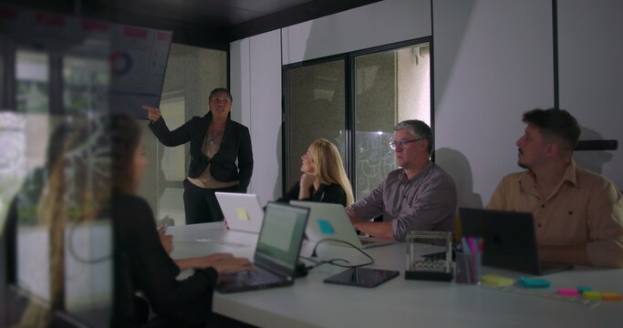 African American professional presenting during team meeting while colleagues observe digital screen in well lit corporate boardroom