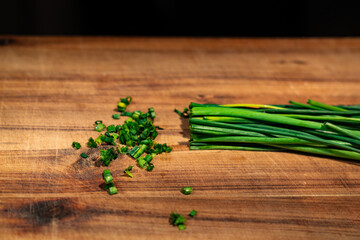 A bunch of chopped green onions are on a wooden cutting board