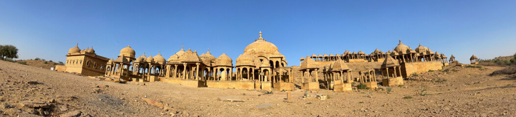 Ancient cenotaphs of Bada Bagh in Jaisalmer, showcasing golden sandstone chhatris under a clear blue sky in the Thar desert.
