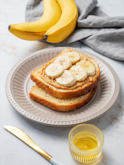 Peanut butter sandwich and banana on a plate on a marble background with honey,