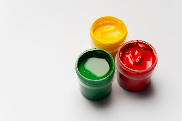 Jars of multi-colored gouache on a white background. Green, red, and yellow traffic light colors.
