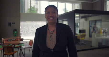 African American woman standing with arms crossed smiling confidently inside modern office space leadership presence professionalism and approachability