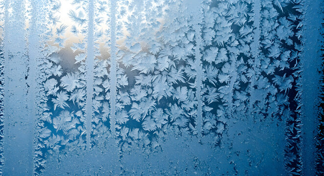 Intricate frost patterns forming delicate ice crystals on a window pane, creating a beautiful winter nature abstract background