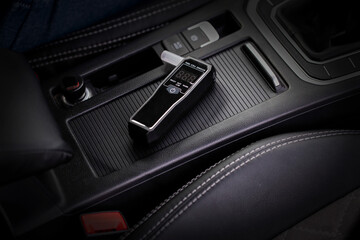 Portable Breathalyzer Rests On Car's Center Console. Digital Device For Measuring Blood Alcohol.