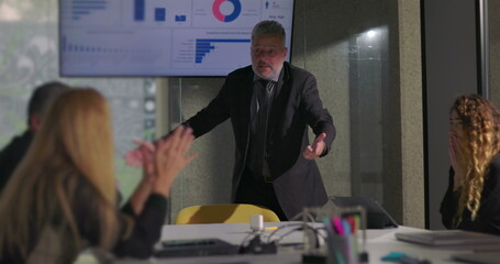 Angry business executive yelling during office meeting with team as colleagues react in shock near data screen in boardroom