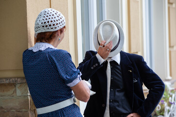 Couple engaged in conversation outdoors while dressed in vintage attire under soft daylight