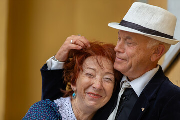 Elderly pair are divided by a joyful moment at the celebration in the room during a sunny day