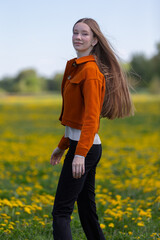 Young woman walking through a field of dandelions on a sunny day in springtime