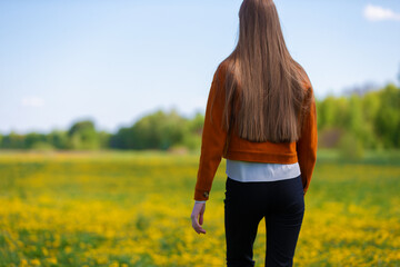 Woman walking through a field of yellow flowers on a sunny day in spring