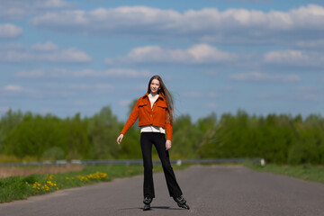 Young woman skating confidently on an empty road surrounded by green trees under a blue sky