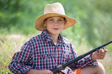 Young boy enjoys a peaceful day fishing by a lush green riverbank during a sunny afternoon