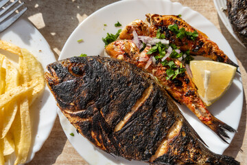El Jem, Tunisia A plateof barbequied fresh fish with lemon and french fries.