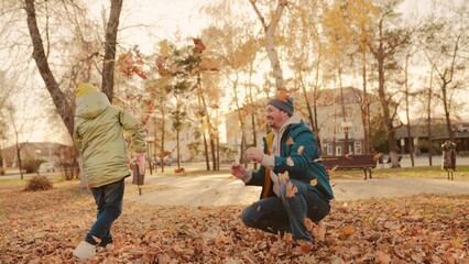 father and little child in an autumn park throw dry leaves up, happy family, live fun with dad, cheerful kid plays with foliage and parent hands throwing leaf fall, parental care of girl, nature walk