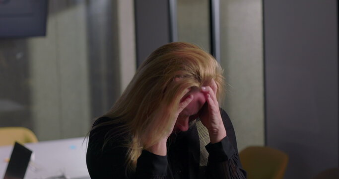 Blonde businesswoman clenching jaw in visible frustration during office meeting, overwhelmed and tense as workplace stress reaches breaking point
